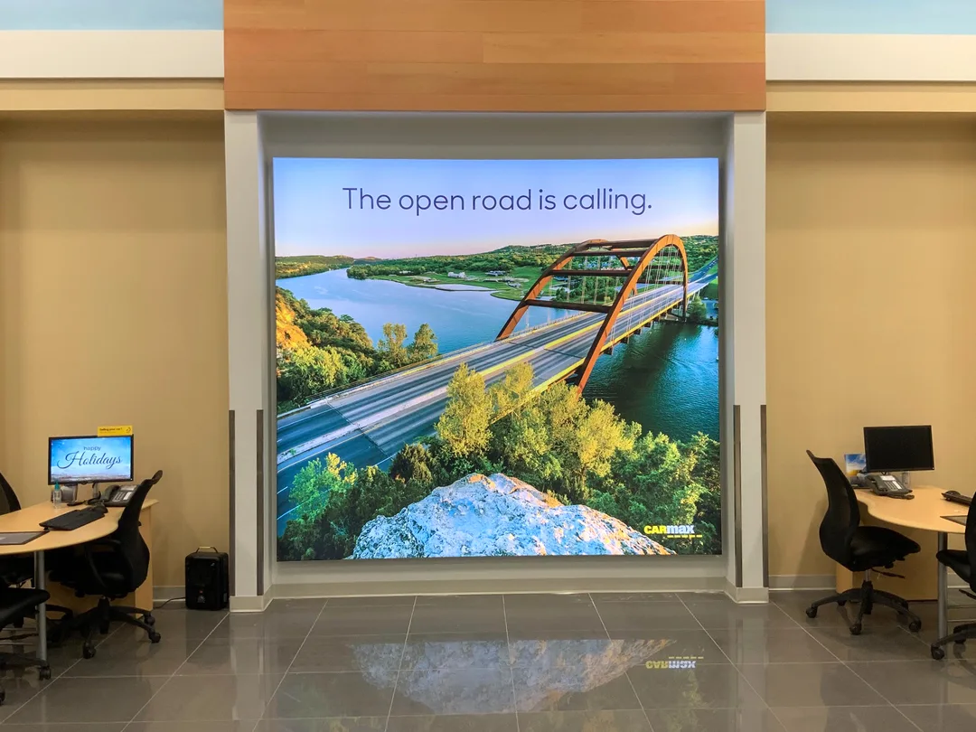 CarMax lightbox evolution with image of highway, car, and trees with slogan on a highlight wall.