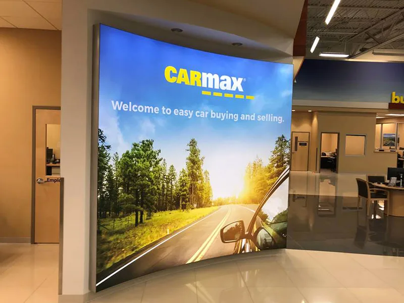 CarMax lightbox evolution with image of highway, car, and trees with slogan on a highlight wall.